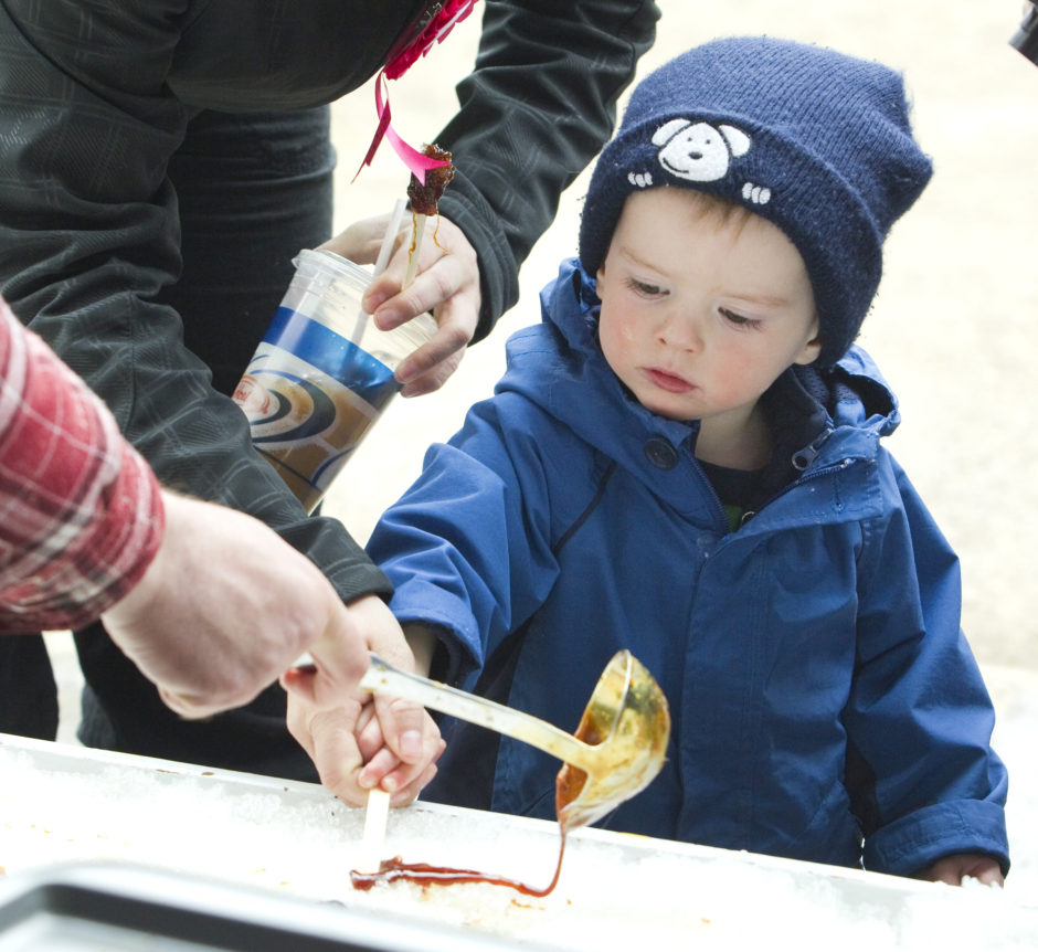 pouring maple syrup on snow boy watching