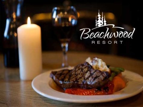 A plate with steak sits besides a lit candle. A logo is shown on top of the image which reads "Beachwood Resort"