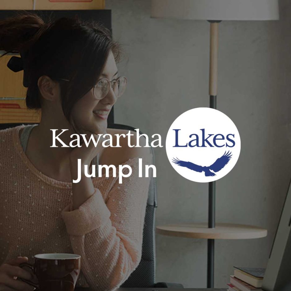 A smiling person sits at her computer. On top of the image is the Kawartha Lakes Jump In logo.