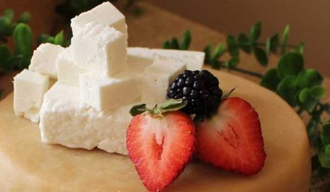 Cubes of cheese beside a sliced strawberry and blackberry