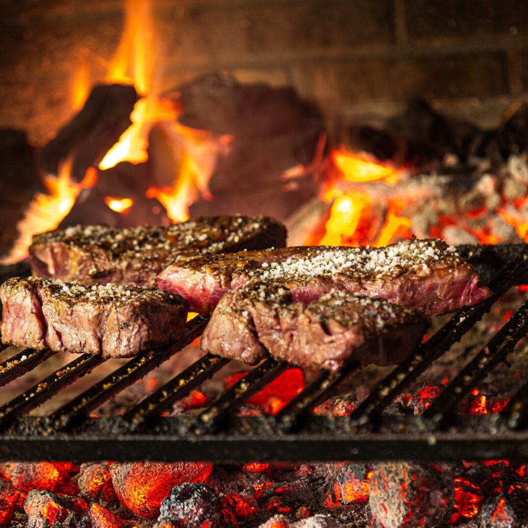 Steaks grilling on a charcoal barbeque