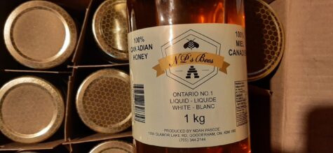 Bottle of honey with a label on it showing it was created by NP's Bees.